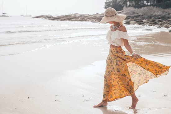 Girl wearing floral maxi skirt walking barefoot on the sea shore, Thailand, Phuket. Bohemian clothing style.